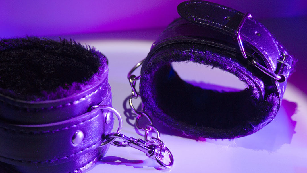 Black leather padded cuffs in purple lighting