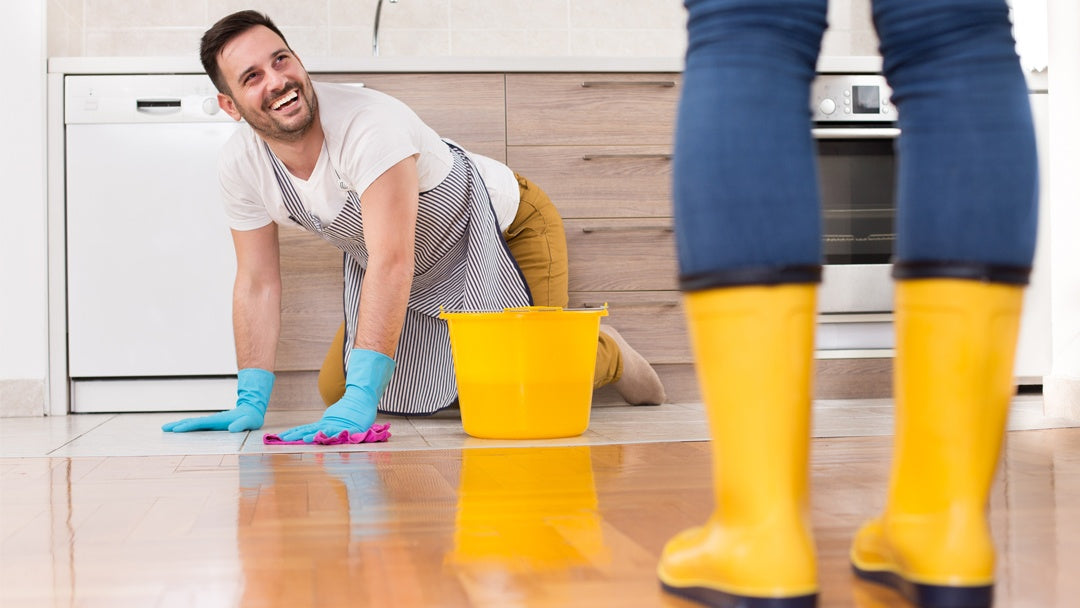 Man washing floor on hands and knees before female partner