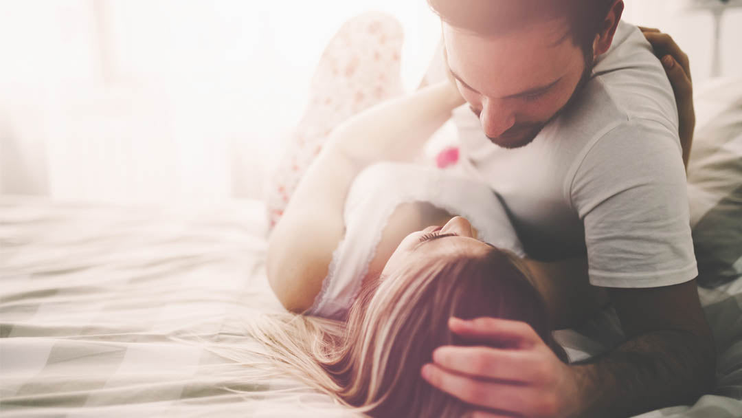 Hazy image of couple embracing in bed at sunrise