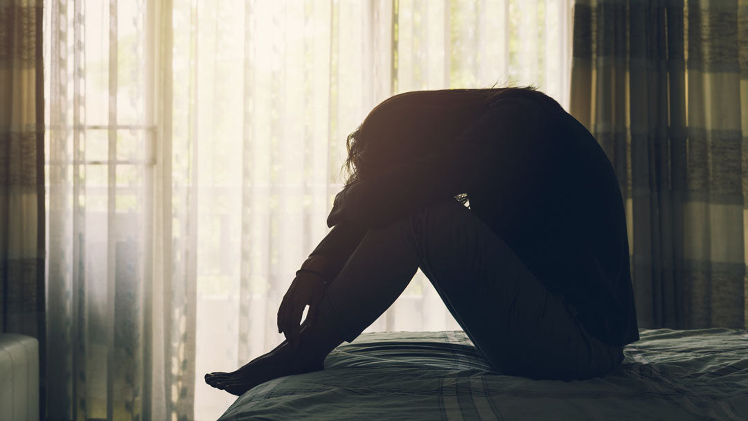 Silhouette of woman sitting on bed upset or depressed