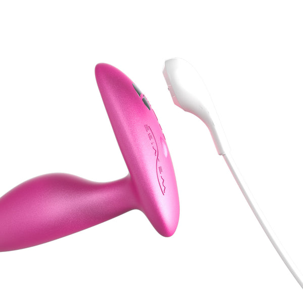 close up of the base of a pink anal plug and the charging cord, showing that the toy is magnetically charged and rechargeable 