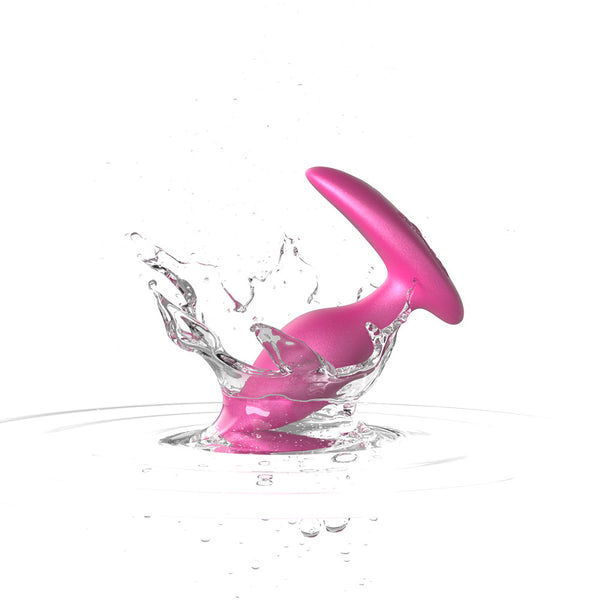 pink silicone butt plug splashes in water to show that the toy is waterproof