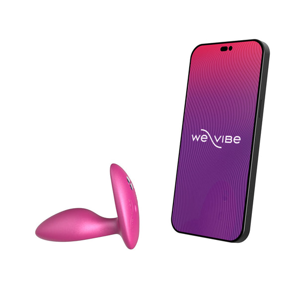 pink silicone butt plug shown next to a cell phone screen that has the we-vibe logo. meant to show that the sex toy is app compatible