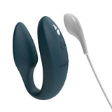 hands-free wearable c-shaped green We-Vibe sync with the charging cord close to the magnetic port. meant to show that the toy is rechargeable 