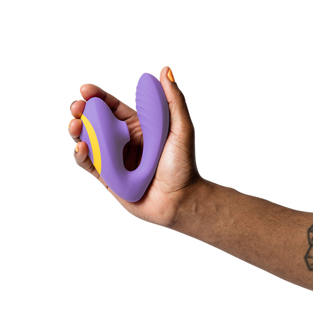 dark brown, gender neutral hand with orange nail polish holds the romp reverb wearable sex toy in the palm of their hand