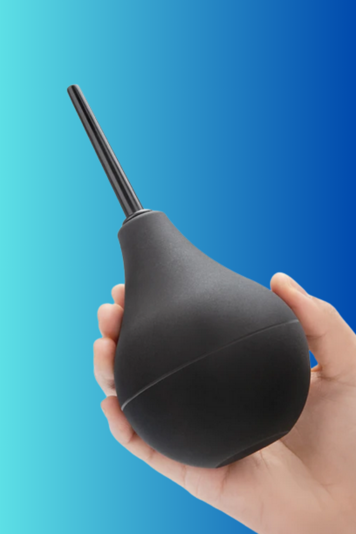 A hand cradling the black B-Vibe Slimline Classic Enema bulb against a turquoise to deep blue gradient, the slim nozzle pointing upward.