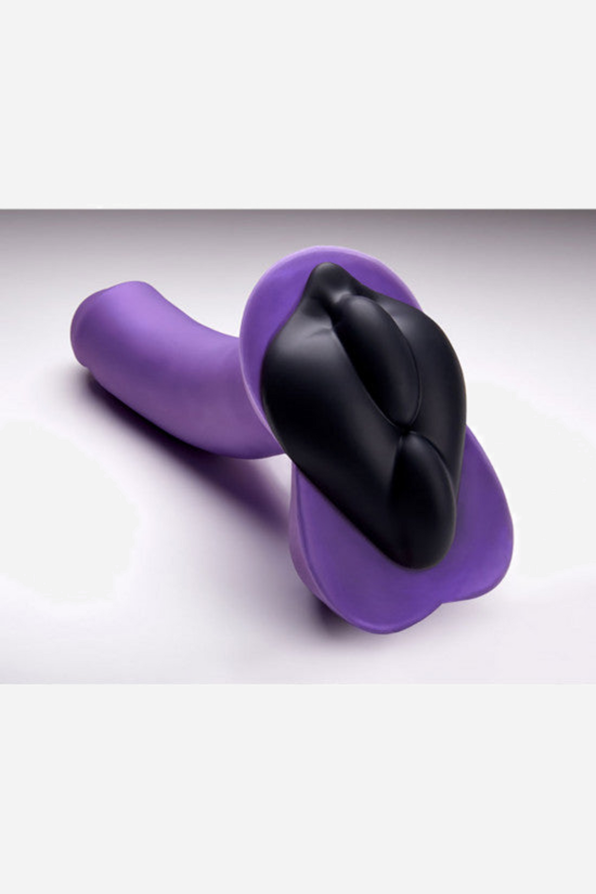 The black b.cush pad slipped over a purple dildo and lying on its side, showing how the cushion sits flat against the toy base