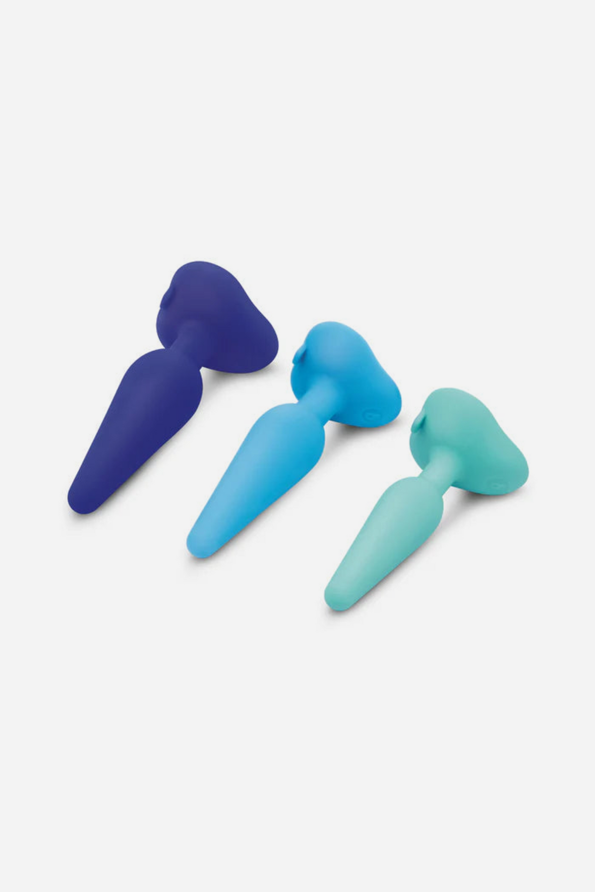 Navy, blue and teal B-Vibe training plugs lying side by side in size order, a graduated set for comfortable anal training and pegging