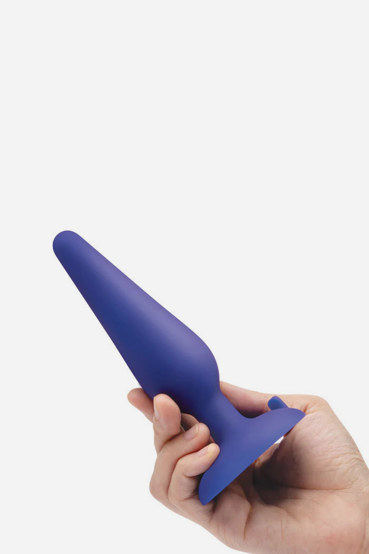 Hand holding the large navy B-Vibe plug by its suction base, showing the size of the biggest plug in the 3-piece anal training kit