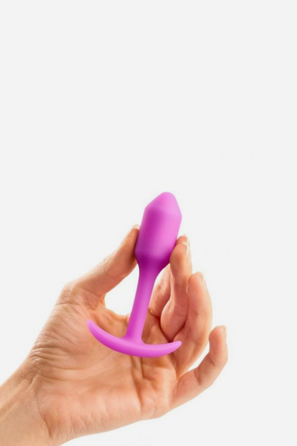 Hand holding the pink B-Vibe Snug Plug 1 small weighted butt plug between the fingers to show its compact, beginner-friendly size