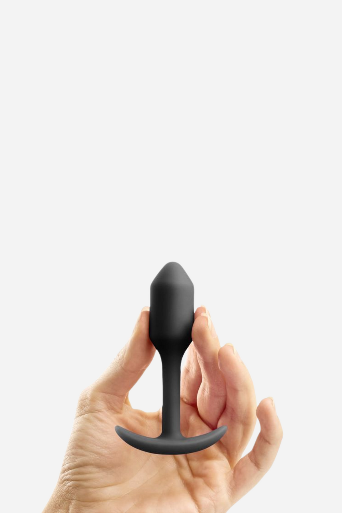 Hand holding the black B-Vibe Snug Plug 1 small weighted butt plug to show its size, with a smooth tapered tip and narrow neck