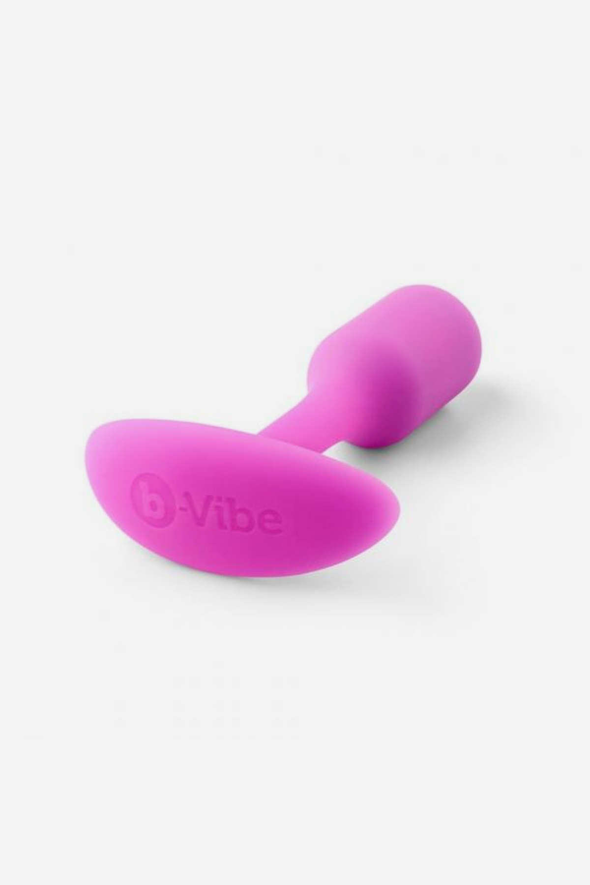 Pink B-Vibe Snug Plug 1 small weighted butt plug lying on its side, showing the soft silicone bulb and the B-Vibe logo on the base