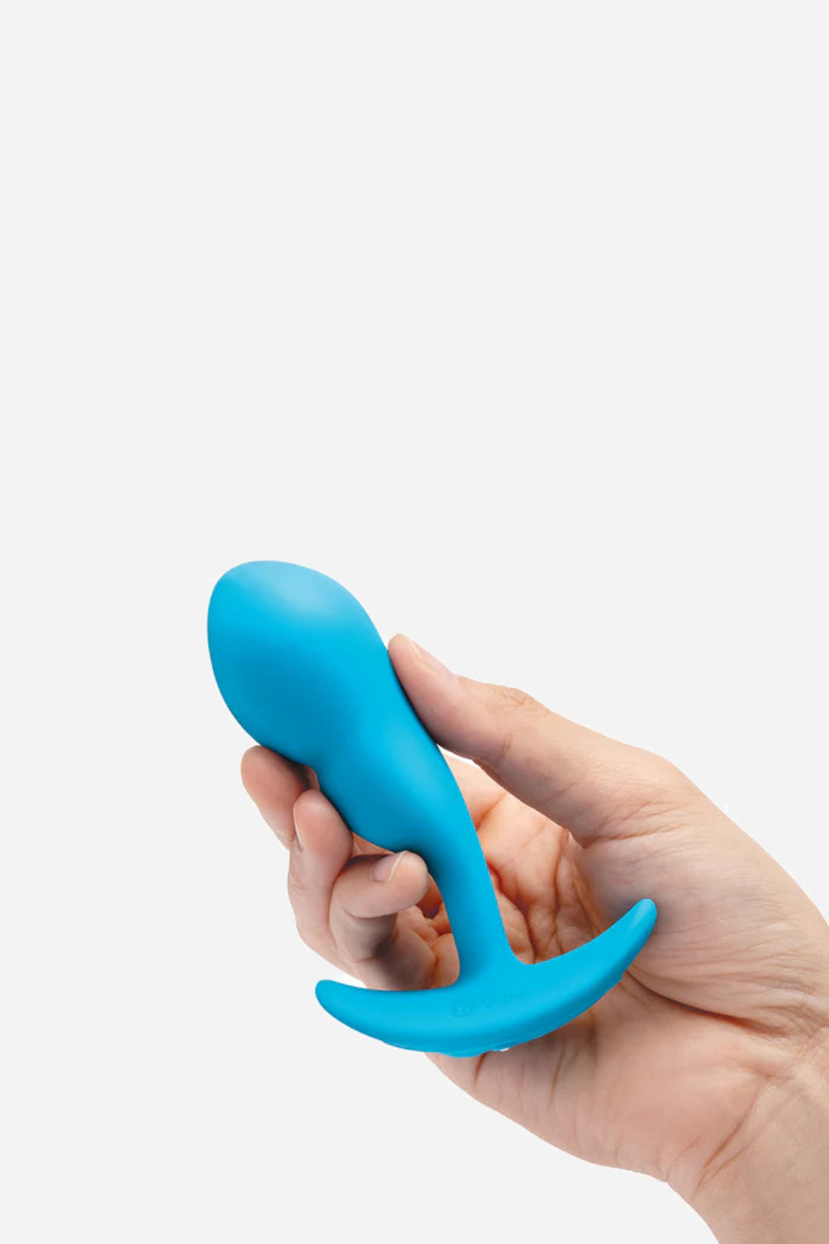 Hand holding the blue B-Vibe Snug Plug 1 upright in the palm, showing the small beginner-friendly size of this vibrating anal plug
