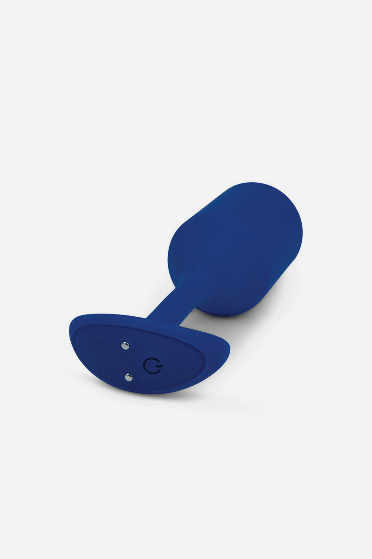 Base of the B-Vibe Vibrating Snug Plug 4 in Navy at an angle, showing the control button and charging port on light grey