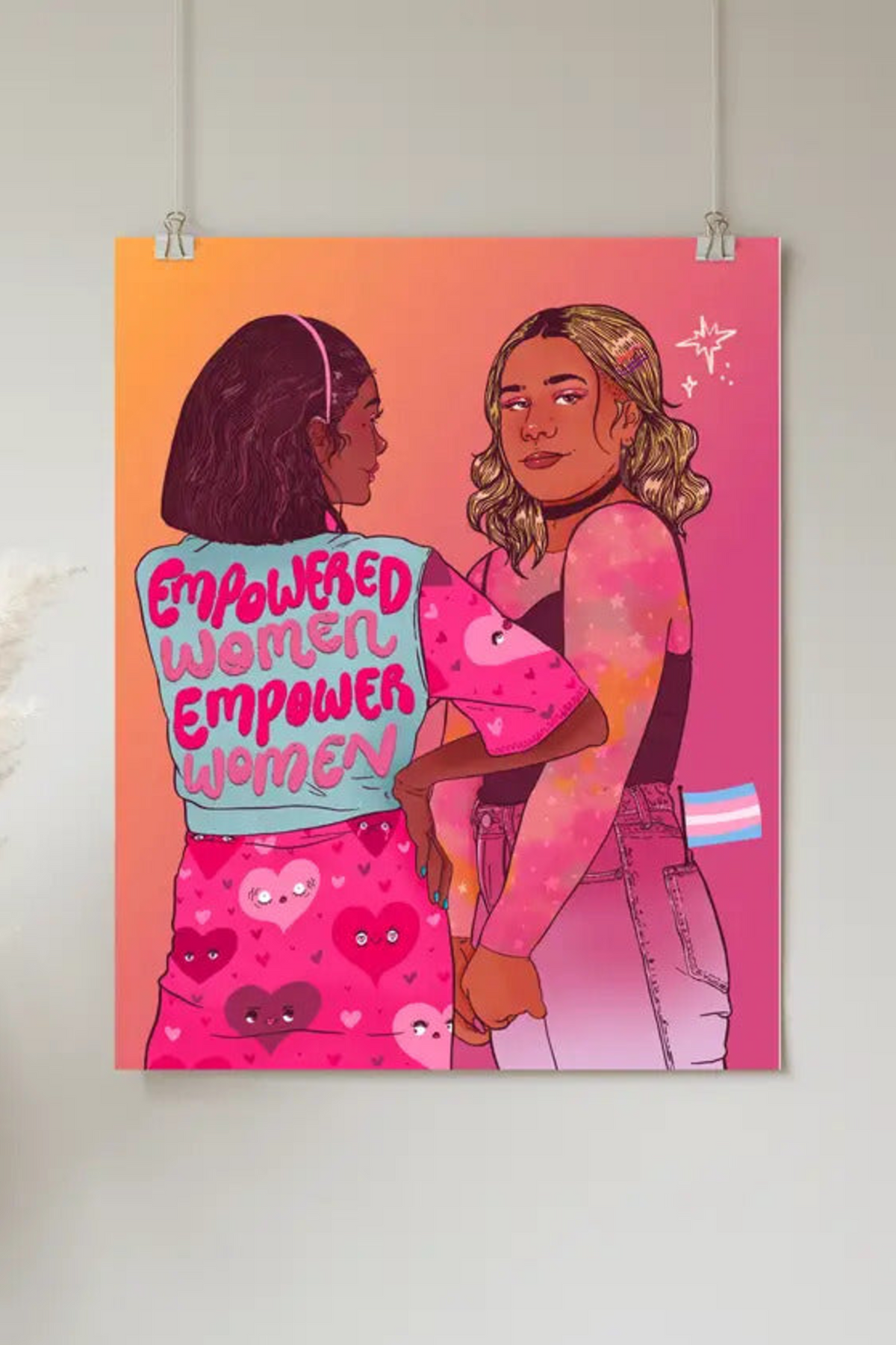Empowered Women Empower Women art print on a grey wall, showing two women embracing on a pink and orange background with hand-lettered text