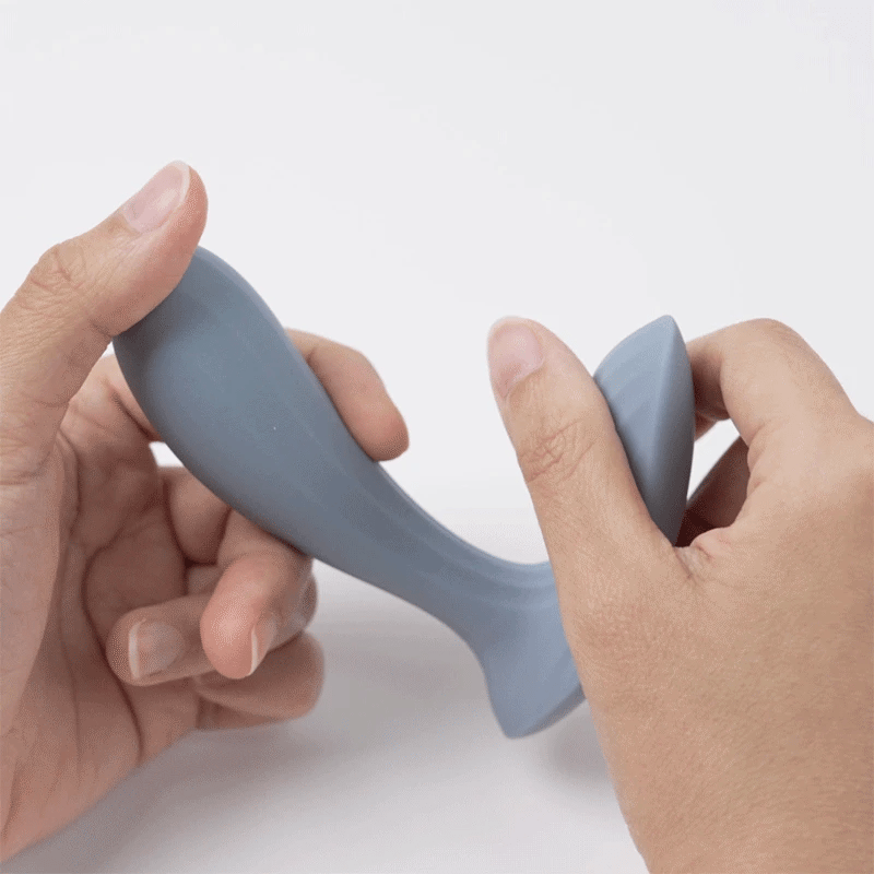 Two hands bending the dusty blue Erica vibe to show how far its flexible silicone body gives before springing back into shape.