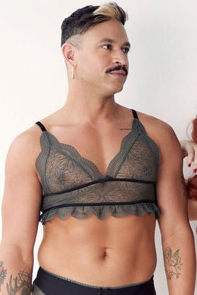 Close front view of a standing model in the Floruisse Ru bralette in slate sage, showing the triangle lace cups and black band
