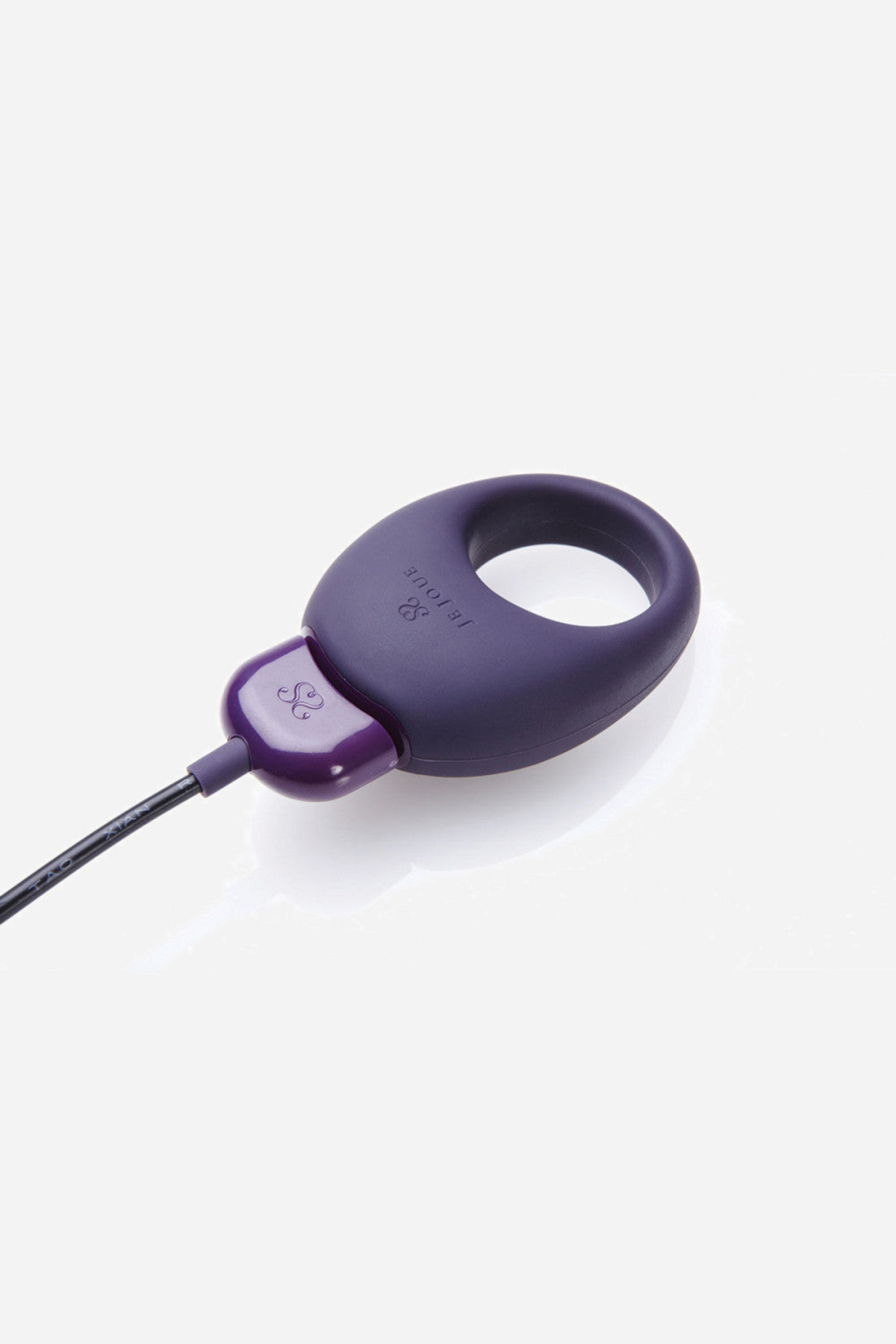 Plum purple Je Joue Mio ring on grey with its magnetic charging cable attached to the two contact points on the motor housing.