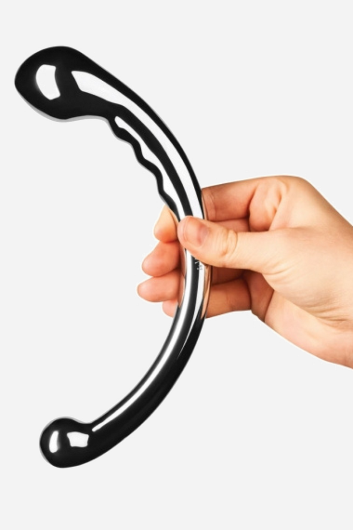 A hand holds the Le Wand Hoop upright by its curve, the polished steel arc catching the light with a rippled shaft and bulbous ends.