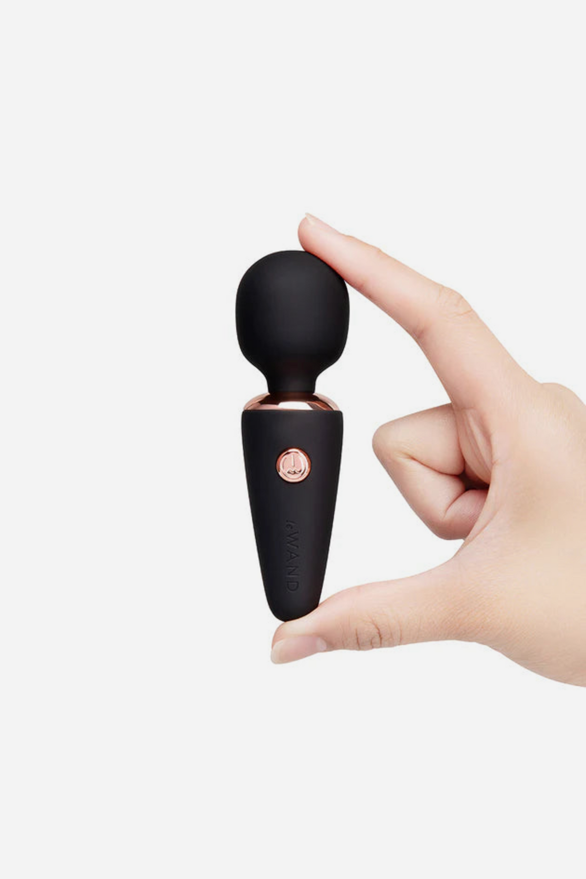 Le Wand Mini Micro Wand in black with rose gold trim, pinched between finger and thumb to show its petite size and soft round head