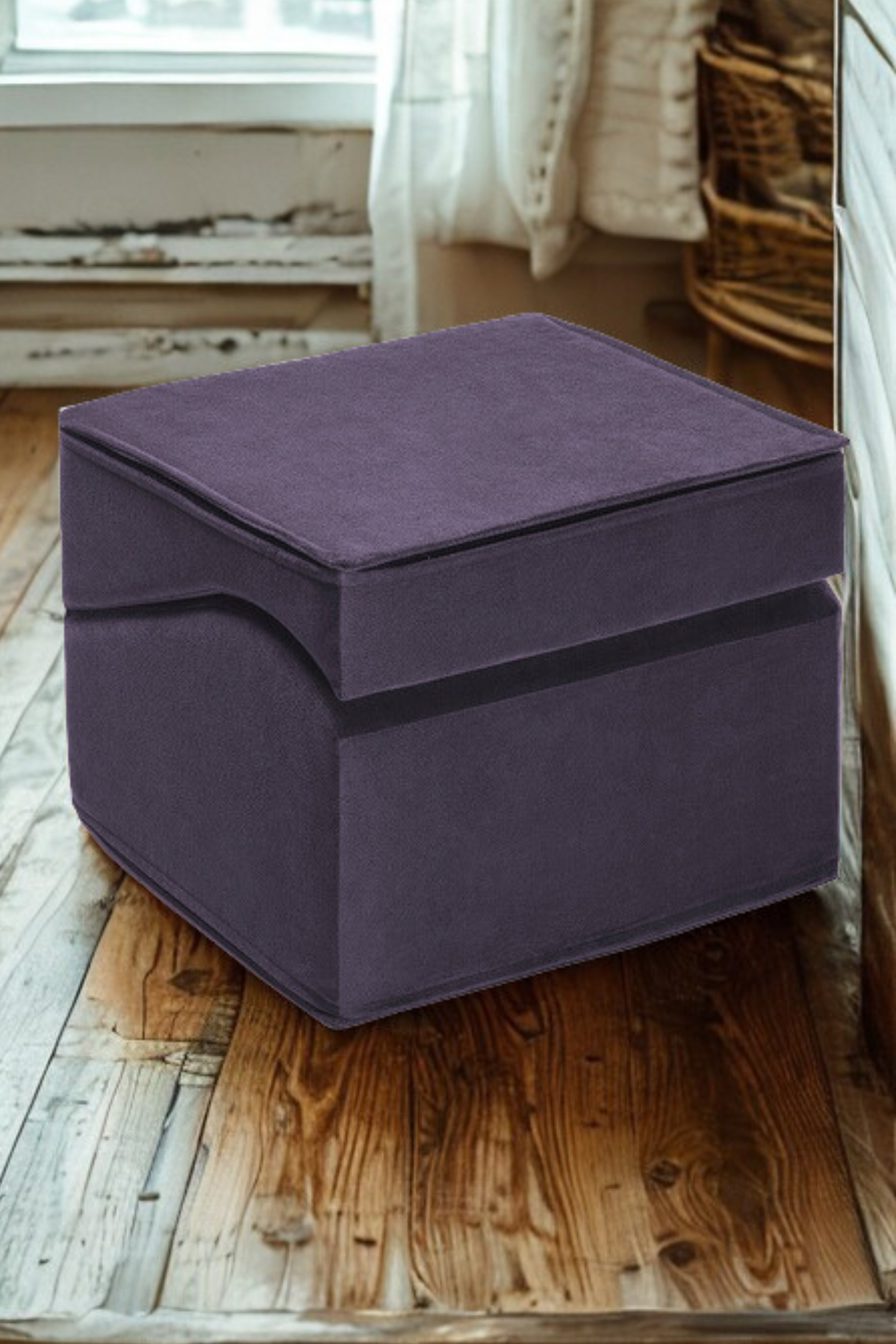 Aubergine Liberator Flip Ramp folded together into a square ottoman, sitting on a wooden floor beside a window and wicker basket