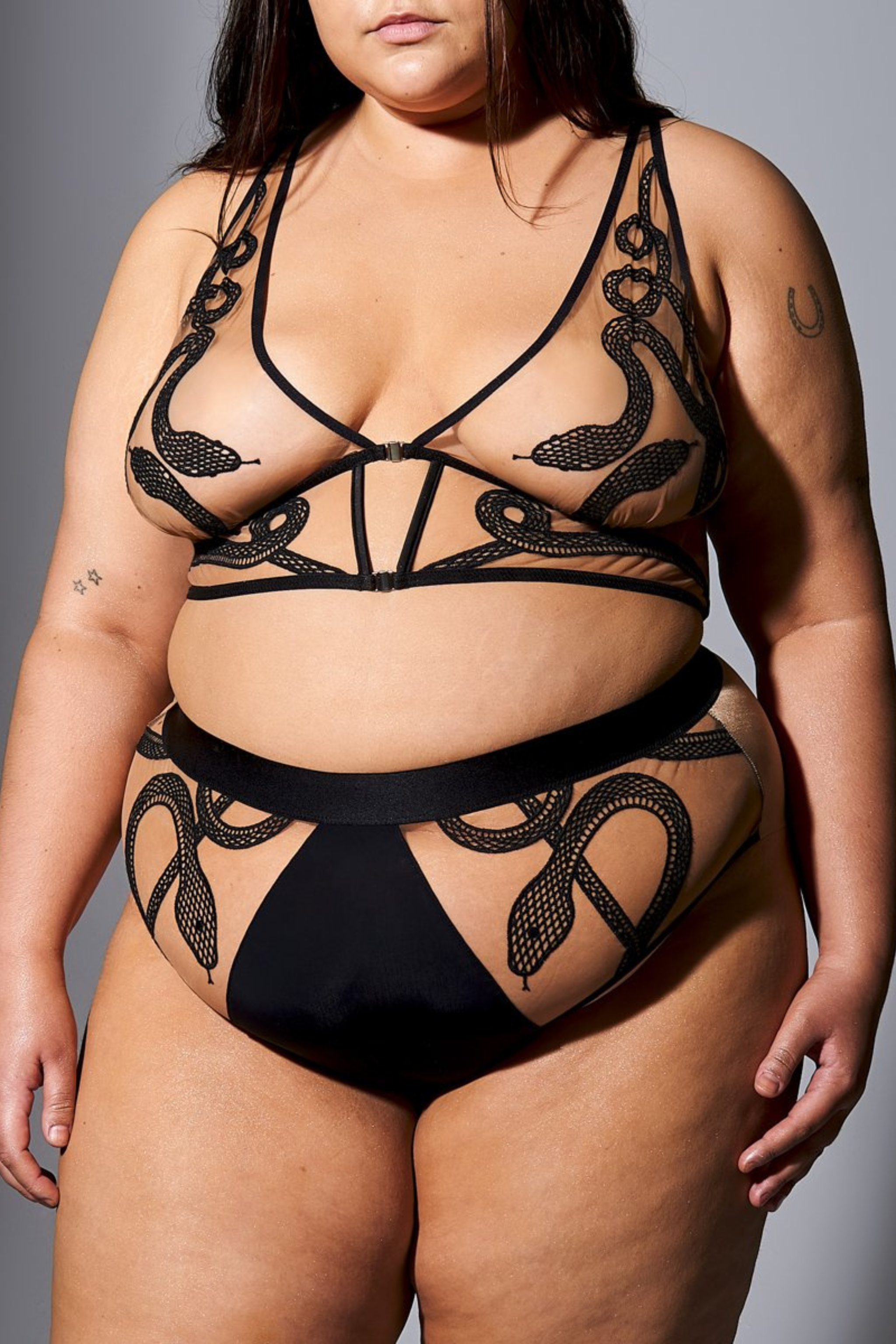 size 1x/2x white model wearing a skin toned tattoo style longline bralette and high waisted bikini panty both pieces with gorgeous snake embroidery