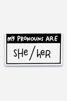 Black and white name-tag style vinyl sticker reading My Pronouns Are in a black header band, with she/her handwritten in the white box below