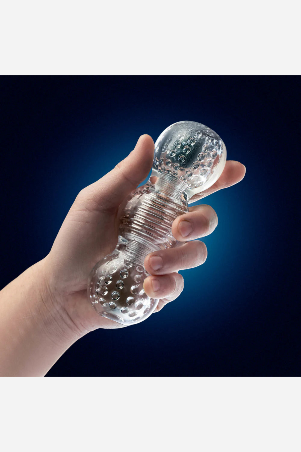 A hand holding the clear Feelz stroker against a deep navy background, the two rounded bulbs of its soft barrel catching the light.