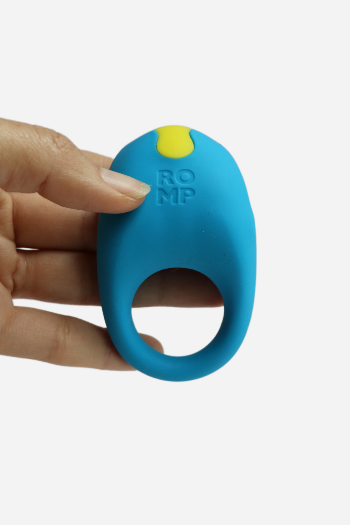 Hand holding the blue Romp Juke beginner's rechargeable vibrating C-ring, showing its compact size and yellow power button, on a grey background