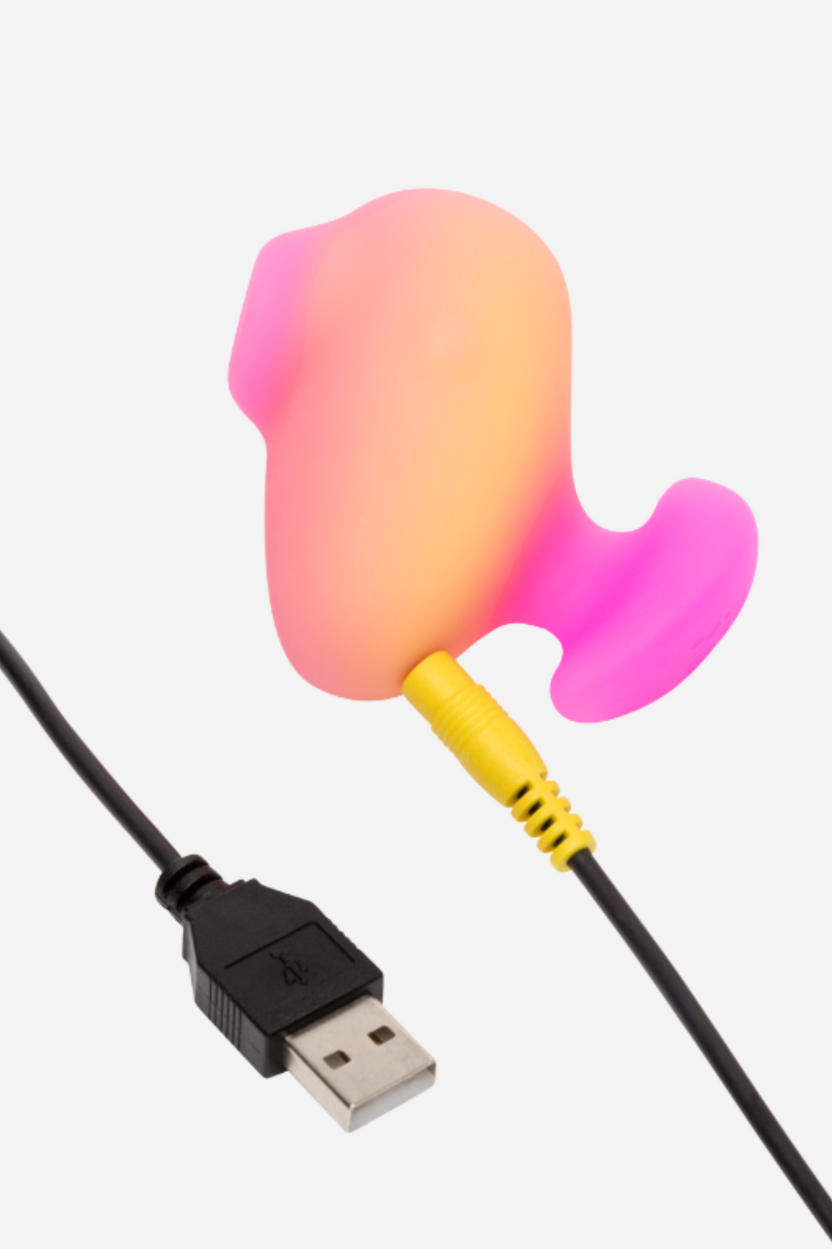 Romp Kiss clitoral suction stimulator plugged into its USB charging cable, showing the rechargeable peach and pink design on a grey background