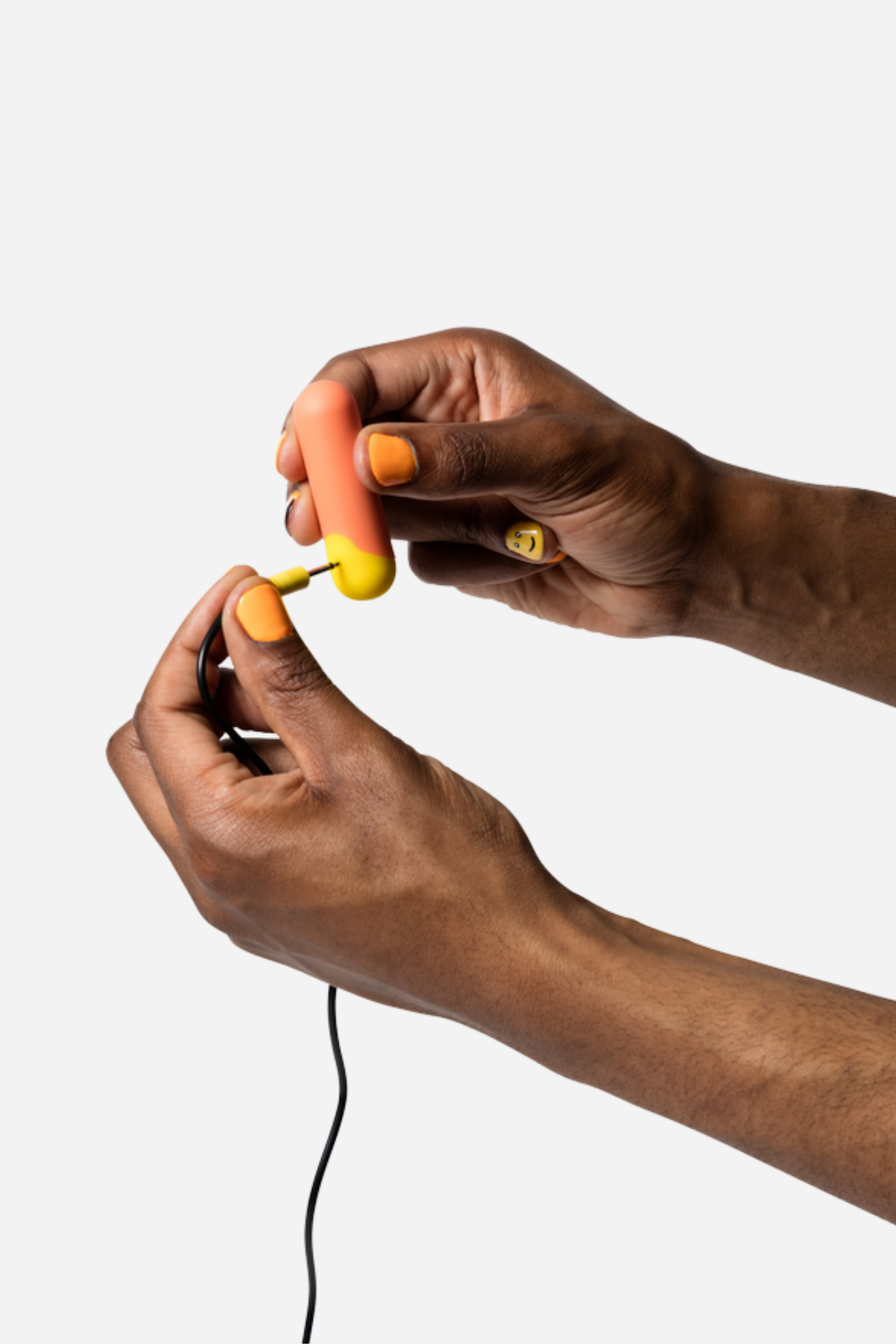 Romp Riot rechargeable bullet vibrator held in two hands while connecting the USB charging cable to its base, on a light grey background