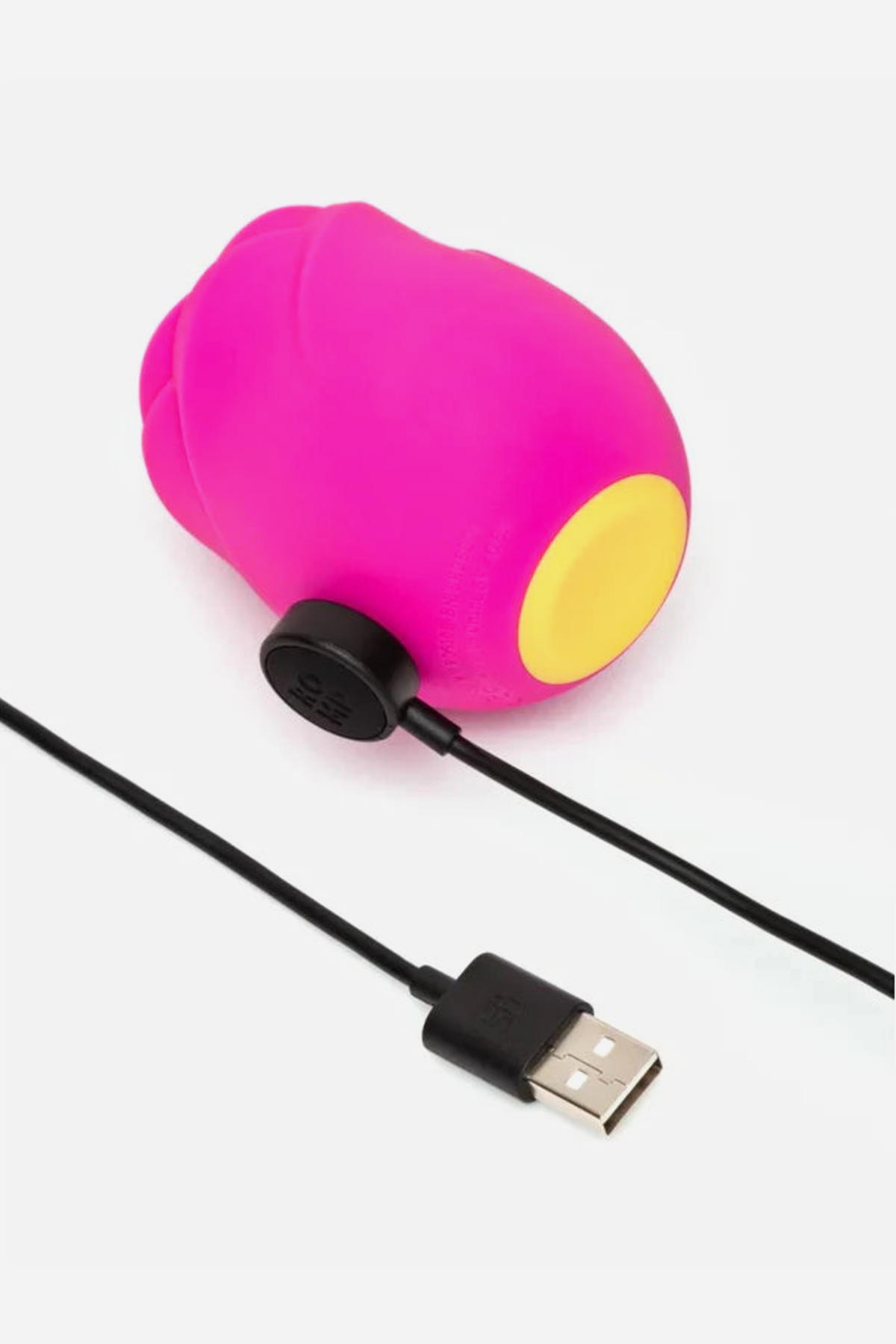 Hot pink Romp Rose 2.0 lying on its side with the magnetic USB charging cable attached to the gold charging contacts on its base