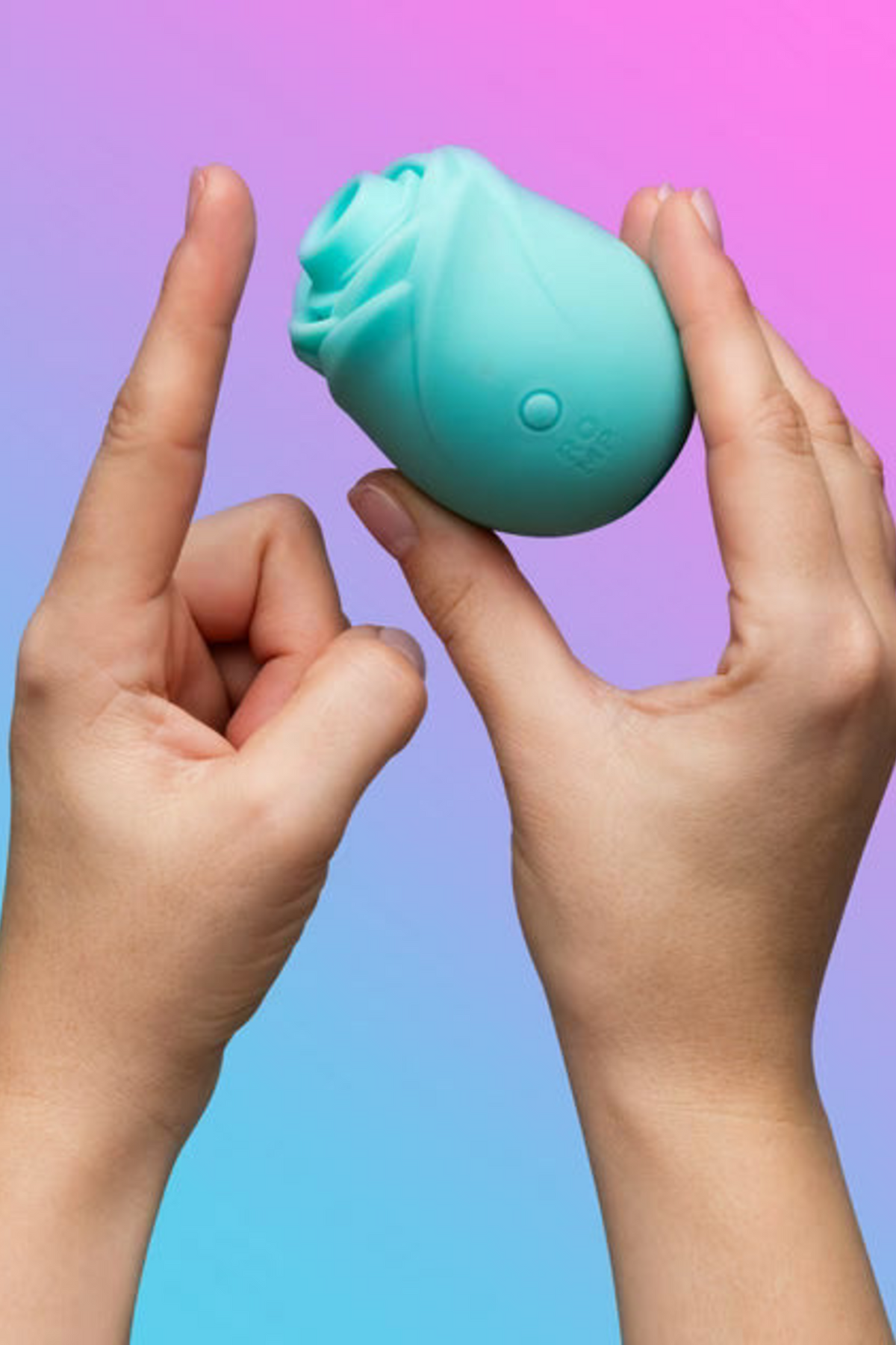 Hands holding the aqua glow-in-the-dark Romp Rose 2.0 against a pink and blue gradient backdrop, showing its compact rosebud size