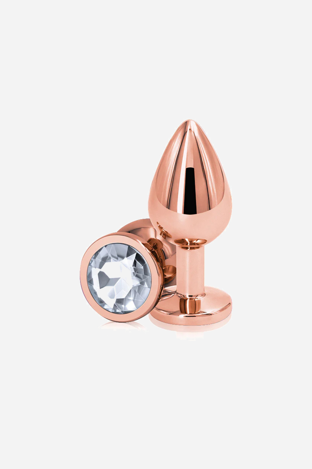 The medium rose gold metal plug standing upright beside its round base, the base set with a clear faceted gem right in the centre