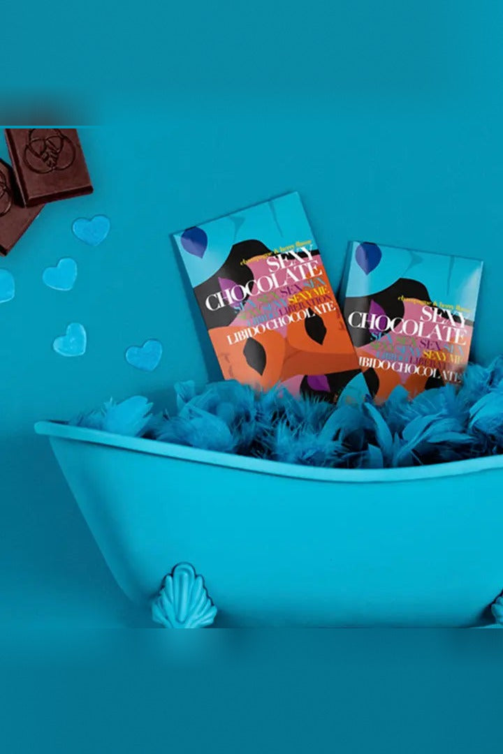 Two Sexy Chocolate Champagne & Berry bars nestled in blue feathers in a small blue clawfoot bathtub with blue hearts