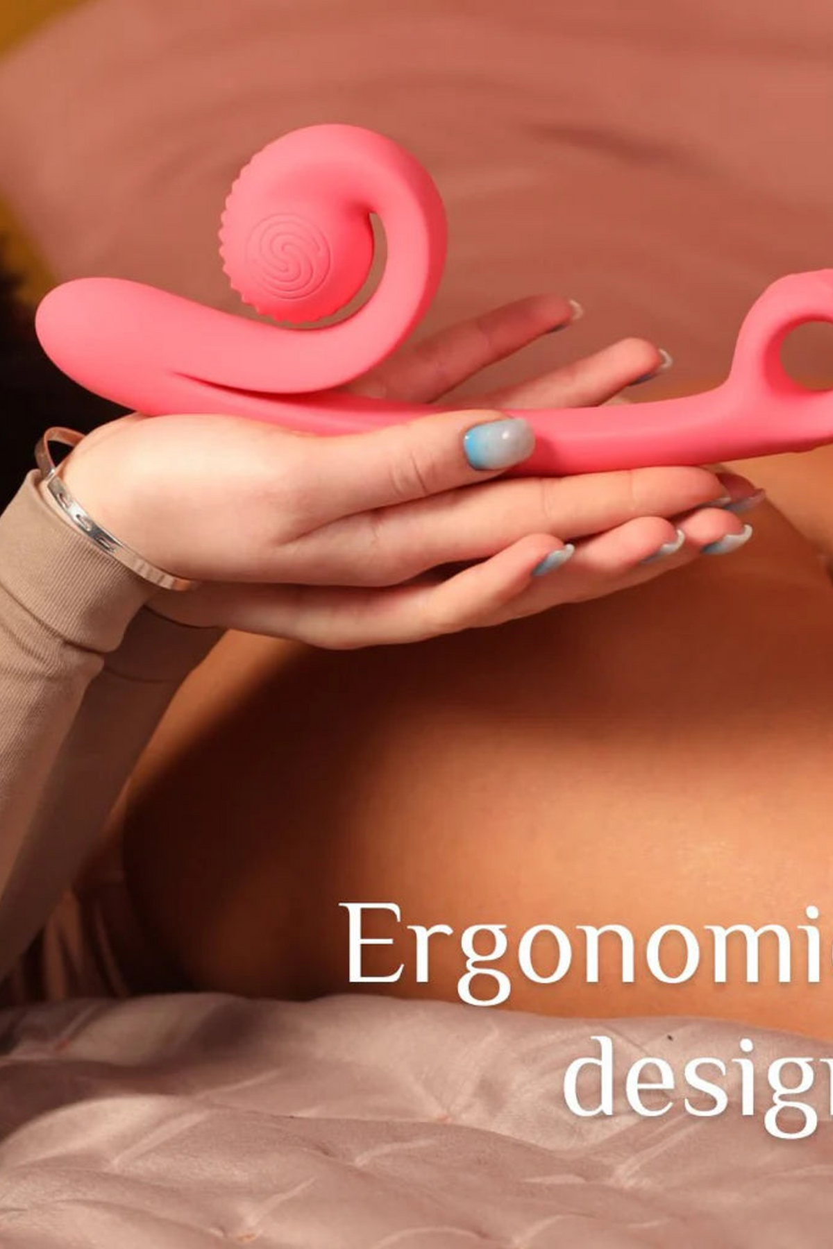 A hand holding the coral Snail Vibe Curve against a warm draped backdrop, captioned Ergonomic design in white lettering across the lower half