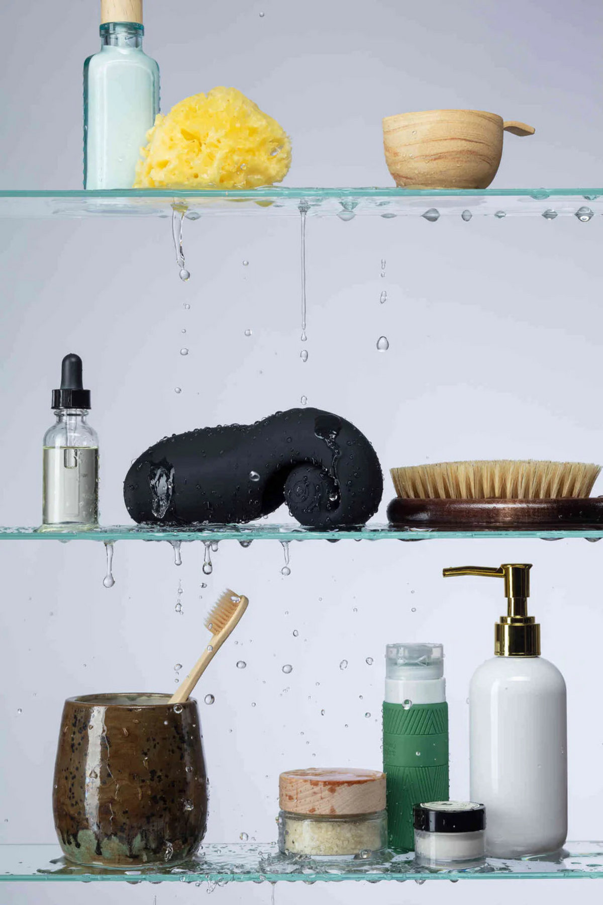 Black Snail Vibe Evo resting on a bathroom shelf among toiletries, showing it is waterproof and discreet enough to store in plain sight