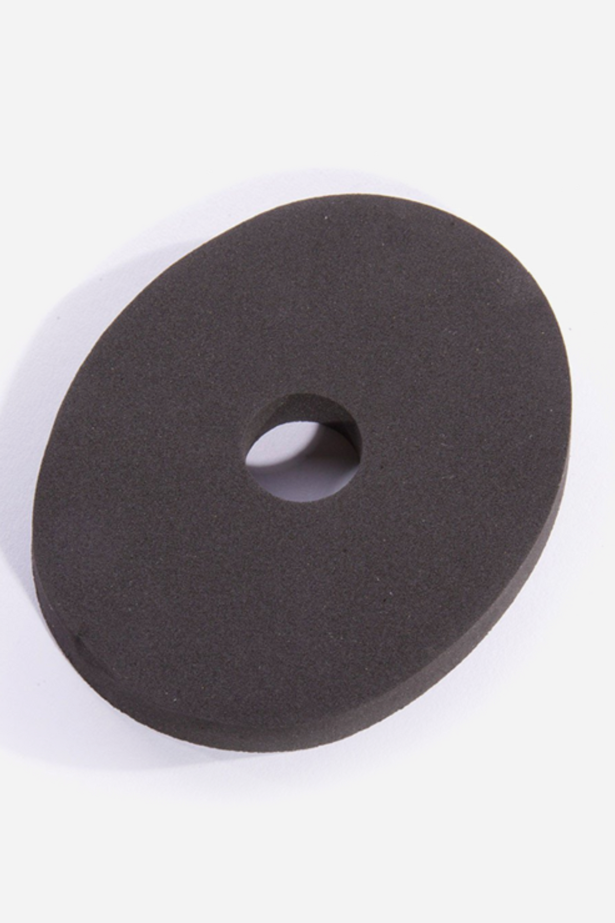 A flat black rubber stabilizer ring with a small central hole, shown at an angle on a plain grey backdrop to show its thickness.