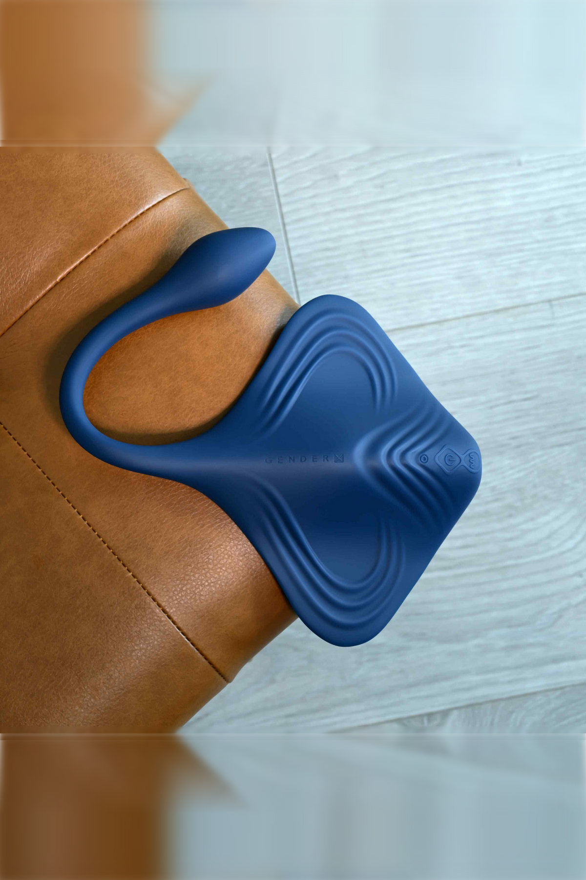 Top-down view of the navy Daily Grind Grinding & Stroking Pad on leather, showing the textured ripple ridges and the curved plug arm