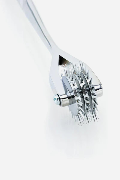 Close-up of the chrome Wartenberg pinwheel head showing the three side-by-side spiked wheels held in a forked metal frame on an axle