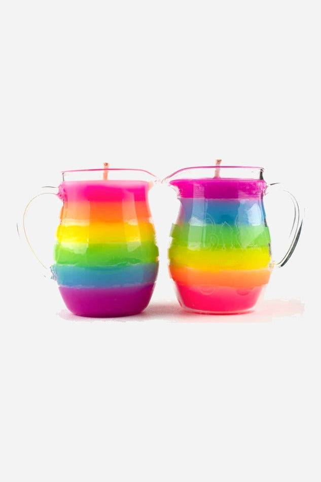 Two rainbow wax play pitcher candles side by side in normal light, showing layered pink, orange, yellow, green, blue and purple wax in glass