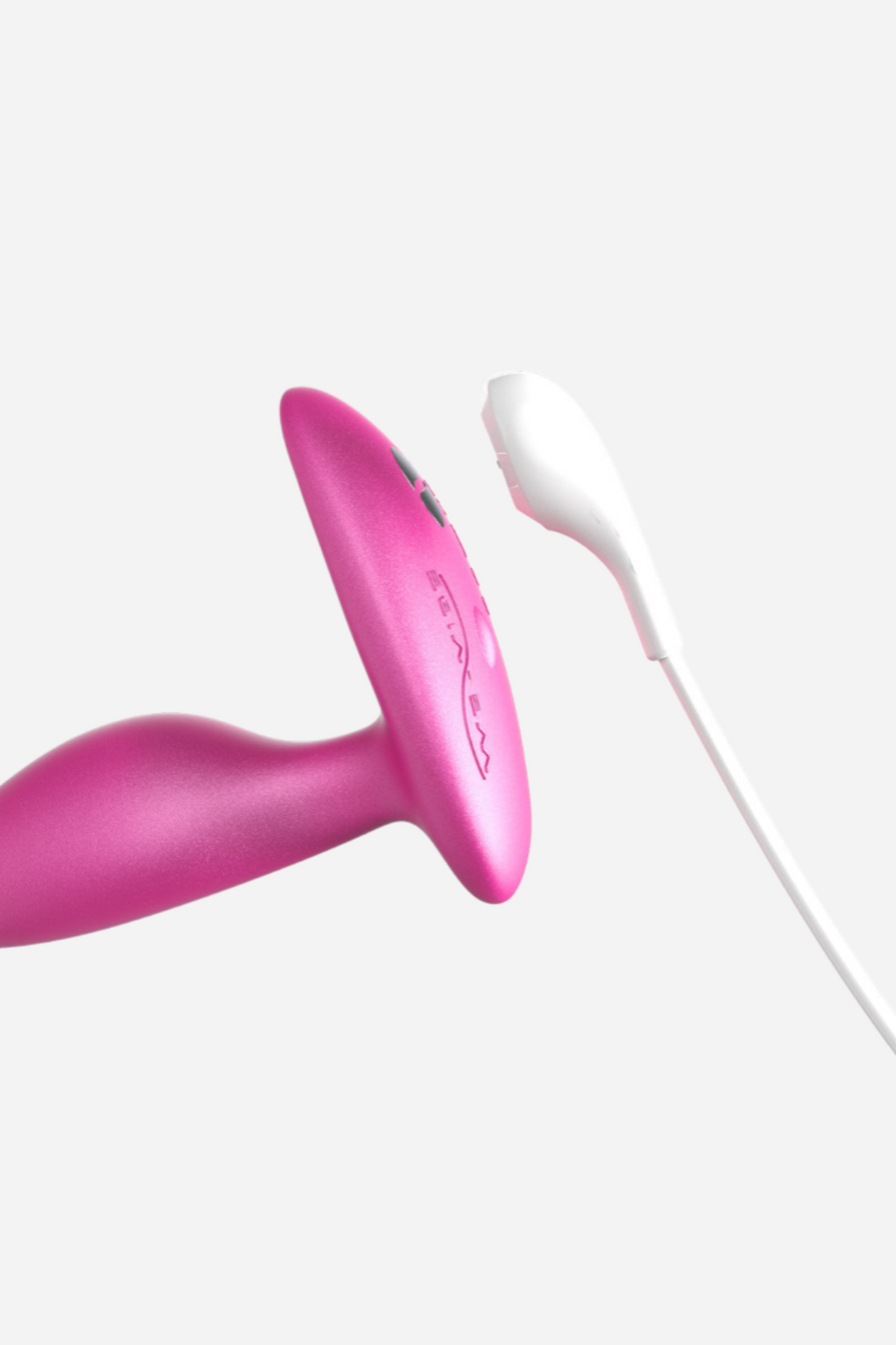 Close-up of the pink We-Vibe Ditto+ base with the white magnetic charging cable about to attach, showing the rechargeable design