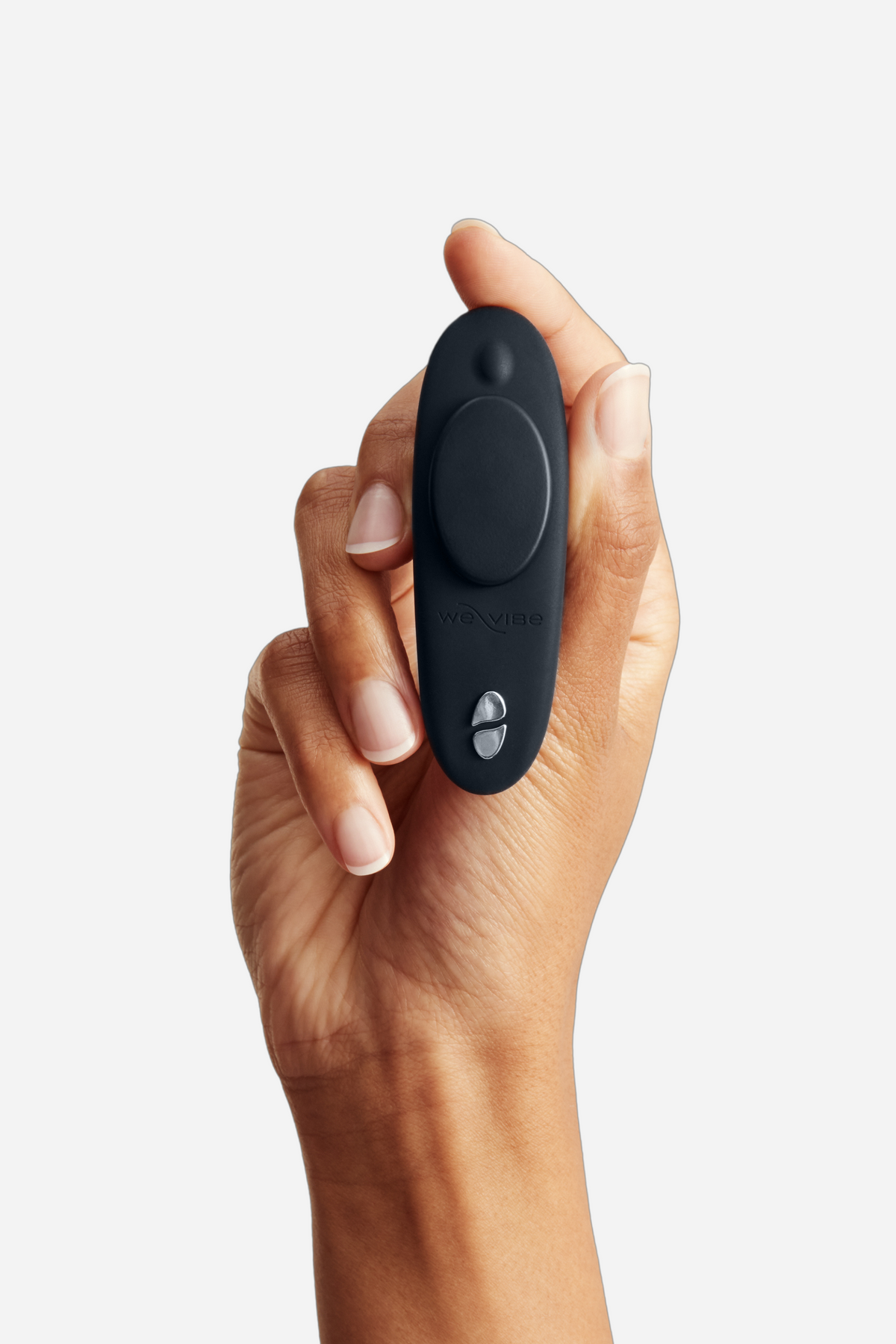 Hand holding the We-Vibe Moxie+ wearable panty vibrator in Black, showing its compact palm-sized shape and magnetic clip on grey