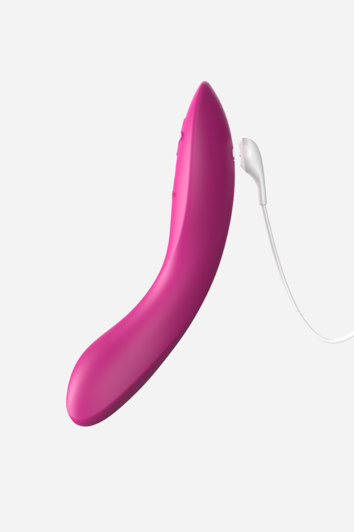 Fuchsia We-Vibe Rave 2 with its white magnetic USB charging cable attached near the base, showing the rechargeable design on light grey