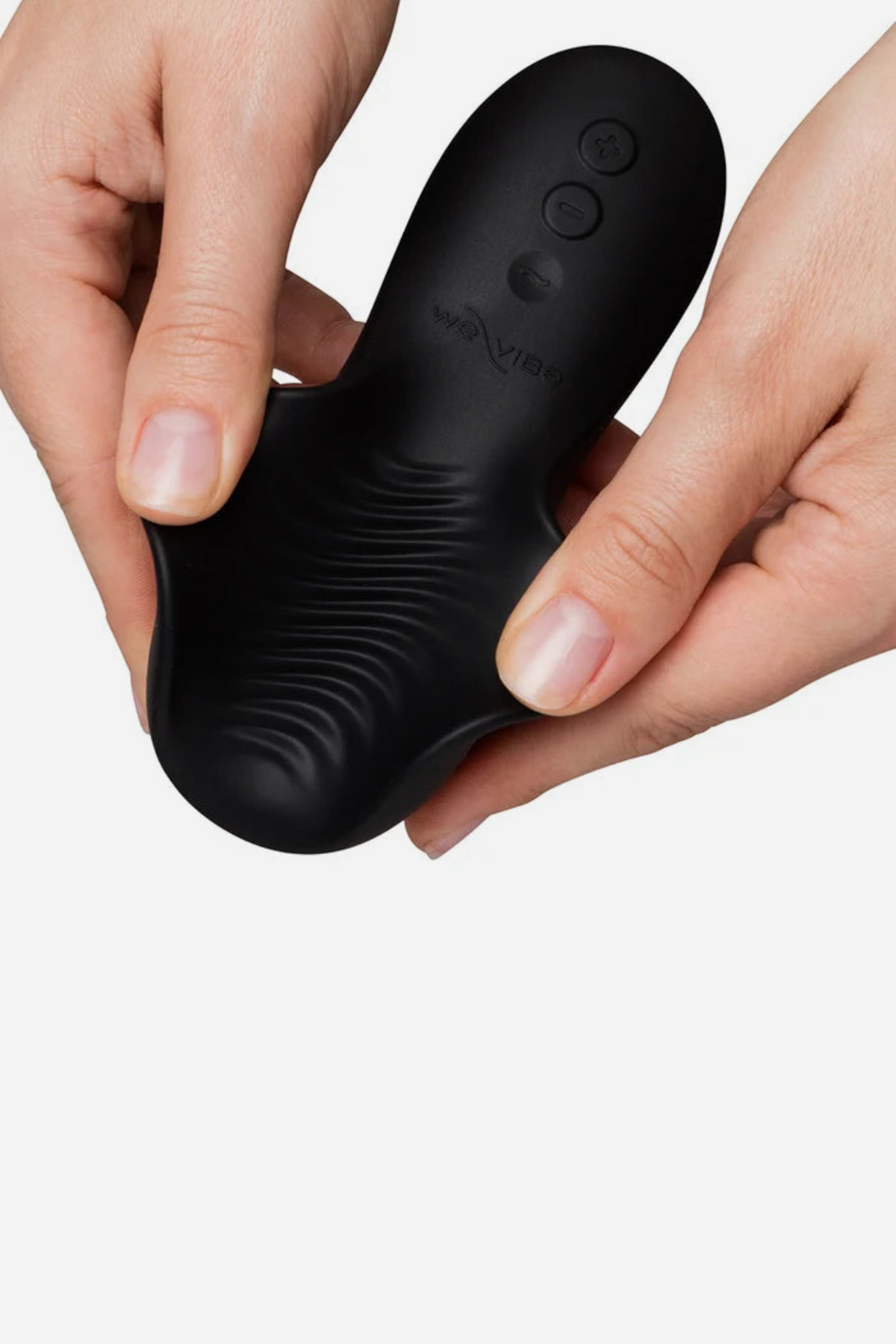 Two hands flexing the black We-Vibe Shared Touch to show its soft bendable silicone, the rippled texture underneath and the buttons on top