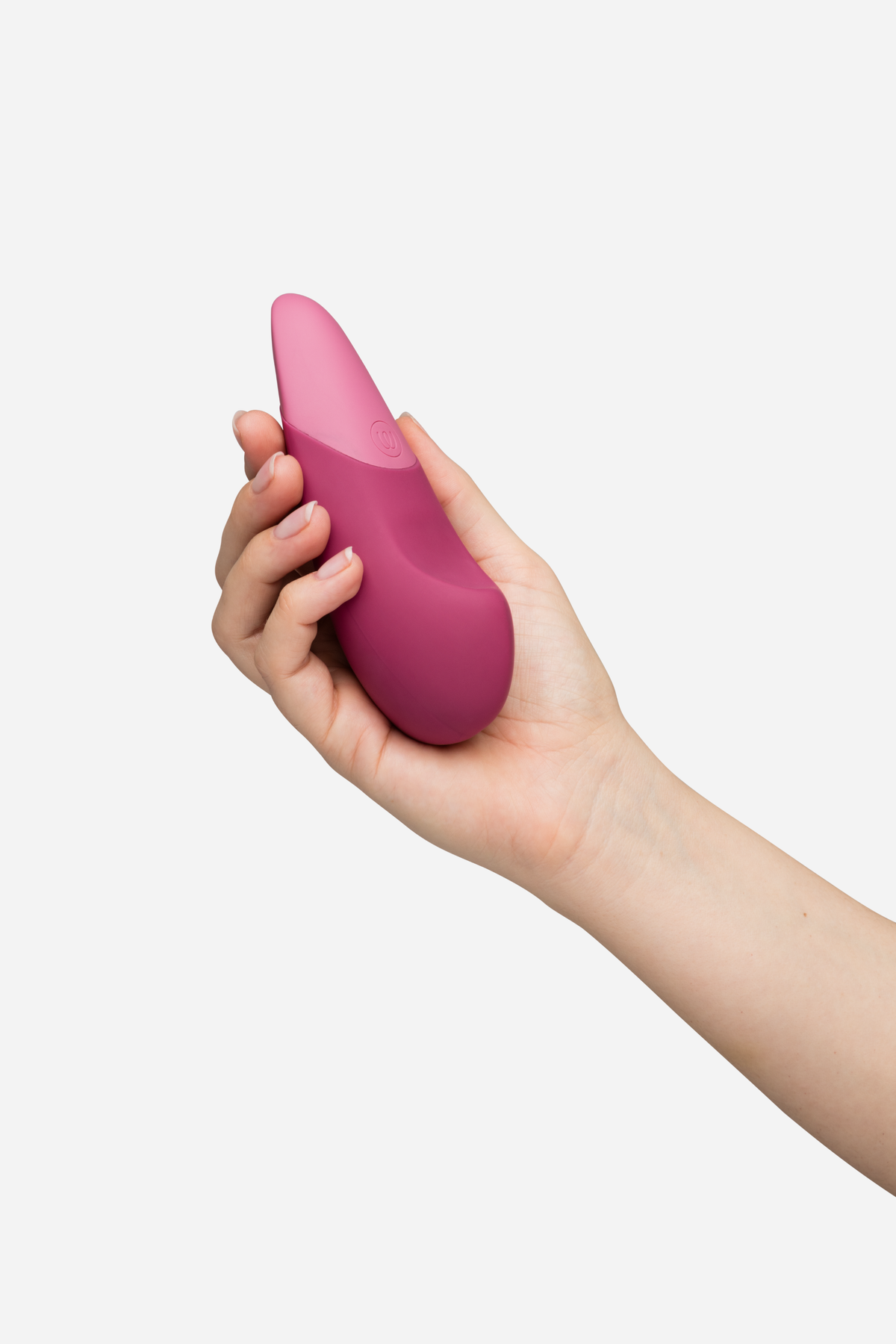 Hand holding the Womanizer Vibe in dusty pink, a smooth pebble-shaped lay-on vibrator with a tapered tip designed for external stimulation