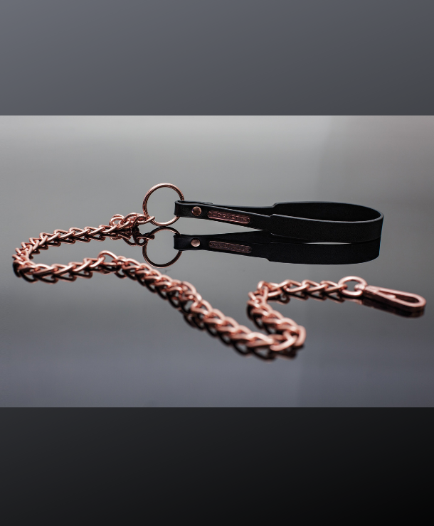 black vegan wrist loops affixed to a rose gold ring and chain leash.