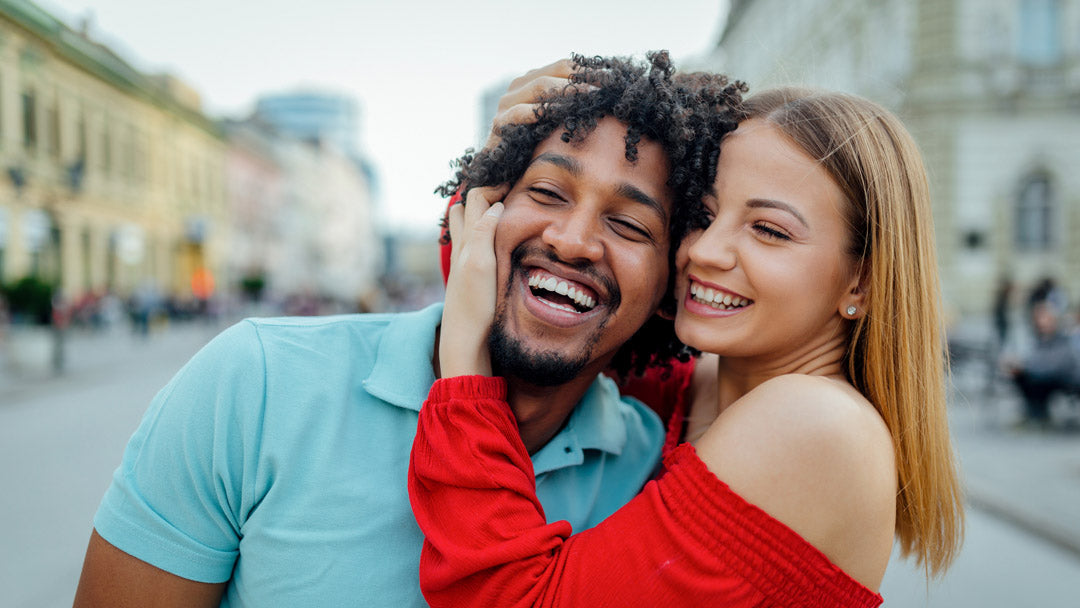Image of interracial couple on a city street laughing and embracing