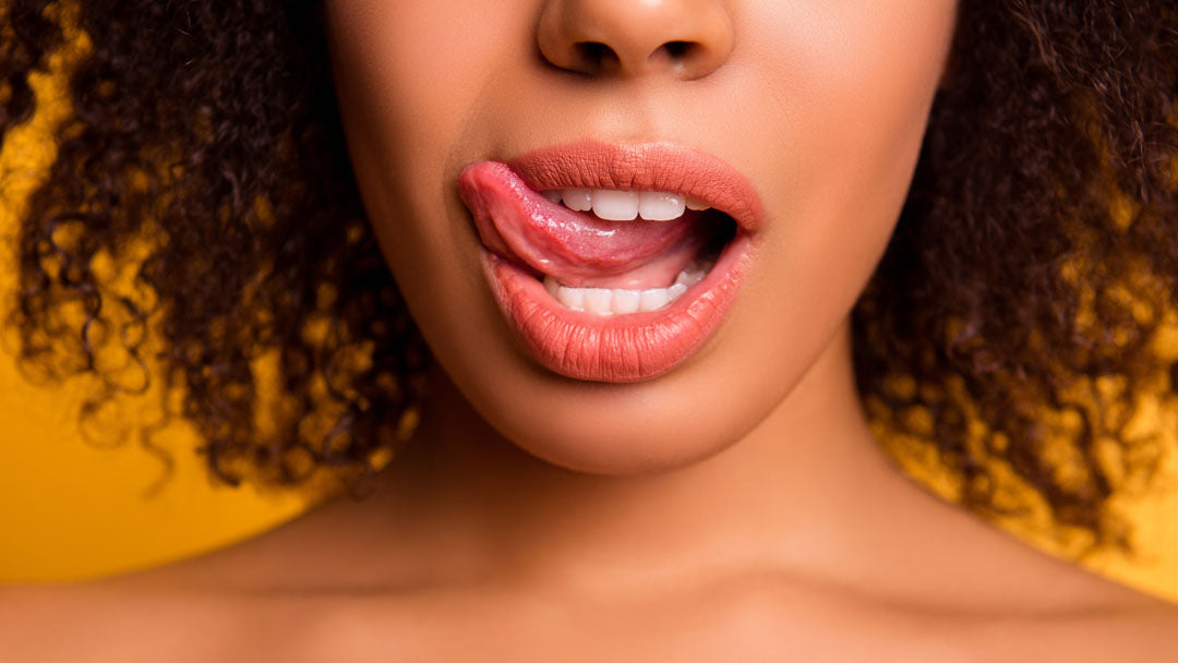 Lower half of woman of color's face, licking her lips