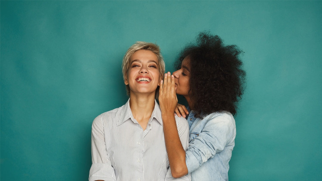 Woman whispering to smiling woman
